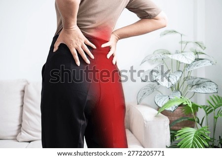 Back view of a woman suffering from sciatica pain, holding her lower back and hip with red glow highlighting the painful area radiating down the leg. Concept of nerve compression and muscle strain