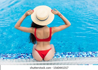 Back View Of Woman In Swimsuit And Hat Which Sitting Near The Pool