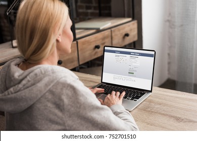 Back View Of Woman Using Laptop With Facebook Social Network Website On Screen  