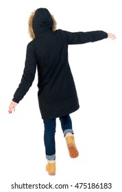 Back view woman in winter jacket Balances waving his arms. Standing young girl in parka. girl in warm winter jacket black balancing on one leg.
