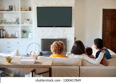 Back view of young African American family sitting on the sofa and watching TV together in their living room - Powered by Shutterstock