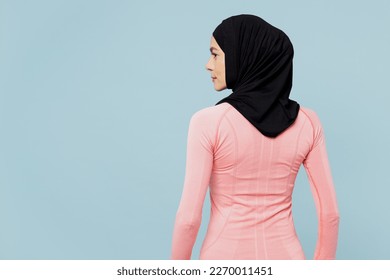 Back view young arabian asian muslim fitness trainer sporty woman wear pink abaya hijab spend time in home gym looking camera isolated on plain blue background studio. Workout sport fit abs concept - Powered by Shutterstock