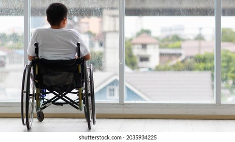 Back view of young Asian handicapped teenage boy without legs sitting on wheel chair and looking to outside of home with copy space on right. - Powered by Shutterstock