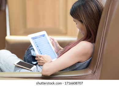 Back View Of Young Asian Woman's Hand Holding Tablet And Smart Phone With Blank Black Screen Lying On Sofa At Home.