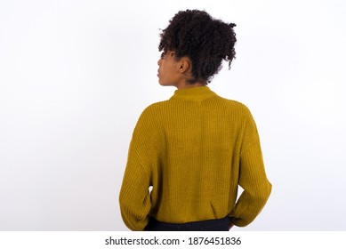 The back view of Young beautiful African American woman wearing knitted sweater against white wall,  Studio Shoot.