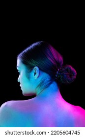 Back view young beautiful girl well  kept skin posing isolated over dark background in purple neon light  Spa  fashion  beauty  health  body   skin care concept 