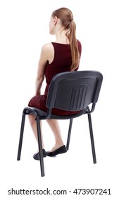 Back View Of Young Beautiful Woman Sitting On Chair. Isolated Over White Background. A Girl In A Burgundy Dress Sitting On A Chair Listening To A Lecture.