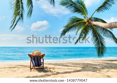 Back view of young beautiful woman sunbathe and relax on tropical beach with copy space. Summer vacation concept                  