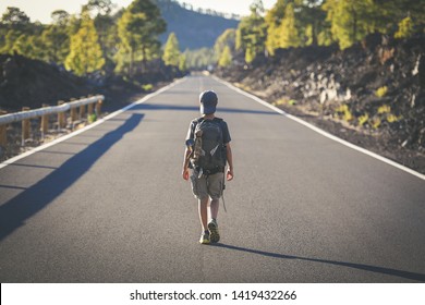 Back view of a young boy walks alone in the middle of the street. Teen with backpack leaving after the end of school Man walking to a new travel adventure. Positive, brave, and adventurous concept.