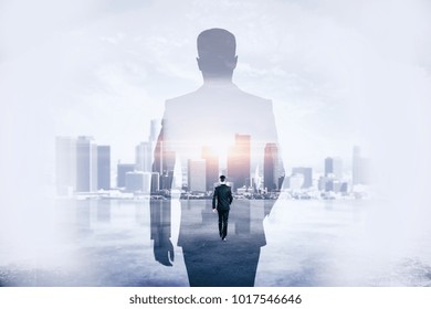 Back view of young businessman walking on abstract city background. Success and development concept. Double exposure 