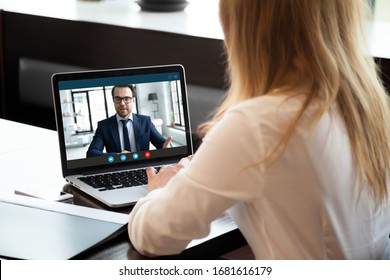 Back view of young businesswoman talk with male business partner using video call on modern laptop, female employee speak consult with businessman on webcam conference, online consultation concept