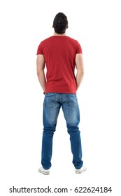 Back View Of Young Casual Man With Hands In Pockets Looking Up. Full Body Length Portrait Isolated Over White Studio Background.