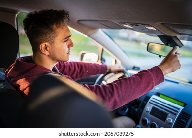 Back View Of Young Caucasian Man Adjusting The Rear Mirror In Car While Driving Or Parking Real People Travel Concept