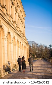 Back view of the young couple and young man near them who are walking together by the palace - Shutterstock ID 1074263612