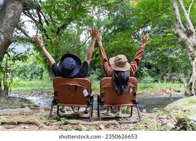 Back view of a young couple sitting in their beautiful nature. Couple sitting on chair holding hands and enjoying beautiful mountain view relaxing weekend