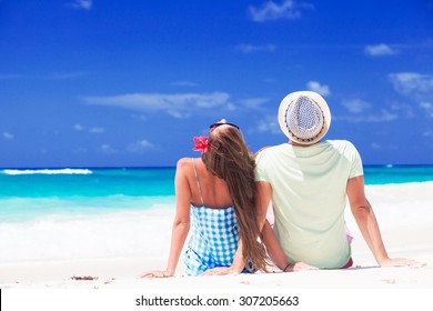 Back View Of Young Couple Sitting By The Sea. Remote Tropical Beaches And Countries. Travel Concept