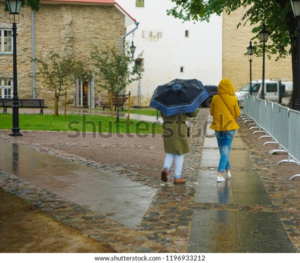 back view of young couple with umbrella\
on cobbles main place in european\
city\
