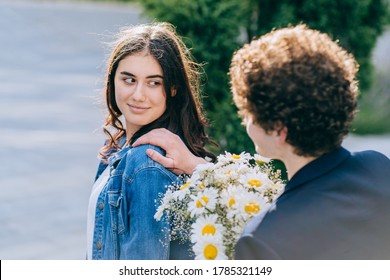 Back View Of Young Curly Caucasian Guy Touch Shoulder, Stops A Beautiful Happy Girl On The City Street. Acquaintance, Rendezvous, Unexpected Meeting Concept.