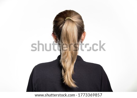 Back view of a young female with dirty blonde hair straight hair in a ponytail wearing small earrings and a black shirt on a white background