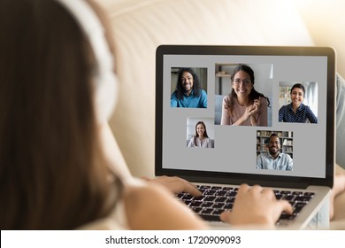 Back view of young female sit rest on sofa ta home talk chat online on video call on laptop with diverse friends, millennial girl have webcam conference on computer with multiracial pals or colleagues - Shutterstock ID 1720909093