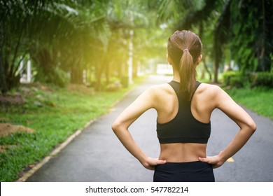 Back View Of Young Fitness Woman Running On The Road In The Morning. People And Sport Concept, Sun Light Flare, Selective Focus