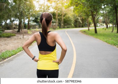 Back View Of Young Fitness Woman Running On The Road In The Morning. People And Sport Concept, Selective Focus