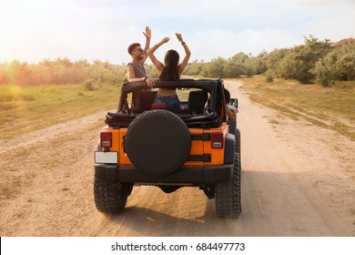 Back View Of Young Friends Standing In A Car With Hands Raised