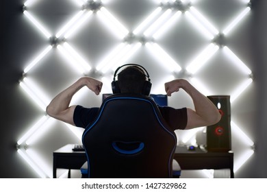 Back View Of Young Gamer Guy In Headphones Screaming And Rejoicing Unleash Power While Playing Video Games On Computer Young Man Shows His Biceps