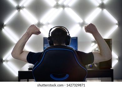 Back View Of Young Gamer Guy In Headphones Screaming And Rejoicing Unleash Power While Playing Video Games On Computer Young Man Shows His Biceps