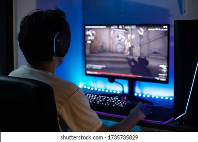 Back view of young gamer playing FPS video games at home