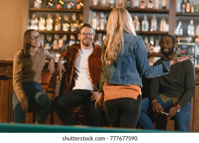 back view of young girl at bar with friends