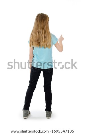 Back view of young girl presses down on something. Isolated on white background. Rear view people collection. backside view of person. The little girl in jeans and blue top is pointing to left
