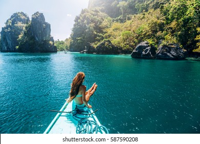 Back view of the young girl relaxing on the boat and looking at the island. Travelling tour in Asia: El Nido, Palawan, Philippines.
