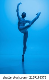 Back view of young and graceful ballet dancer isolated on blue studio background in neon light. Art, motion, action, flexibility, inspiration concept. Contemp performance, dance