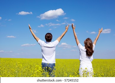 Back View Of Young Guy And Girl Praising God In Yellow Meadow At Summer