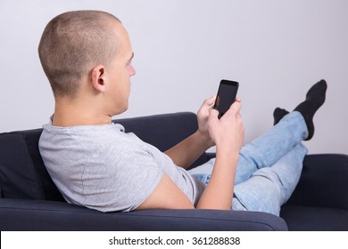 Back View Of Young Handsome Man Using Smart Phone At Home