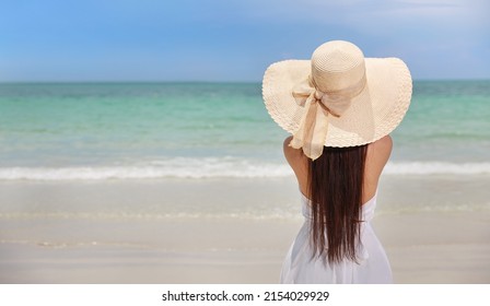 Back view young happiness asian traveller woman in white dress and hat standing on beautiful sandy beach. Cute girl enjoy her tropical sea on relax holiday vacation during summer time and sunshine day - Shutterstock ID 2154029929