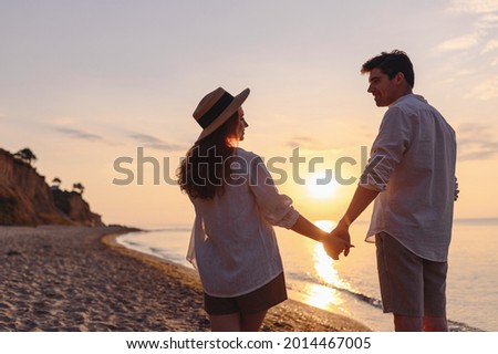 Back view young happy lovely couple two friends family man woman 20s in summer clothes hold hands walking stroll together at sunrise over sea beach ocean outdoor exotic seaside in summer day evening