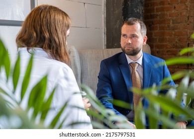 Back View Of Young Lady In Business Dress And Handsome Middle-aged Successful Male Talking At Cafe Table. Business People Talking Over Coffee In A Cafe