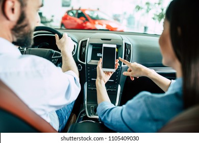 Back view of young Lover couple in car, man driving in city and woman using navigation on mobile phone or some apps