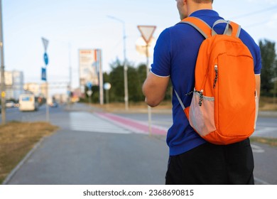 Back view of a young man with a backpack on the street.