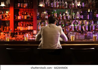 Back view of a young man drinking beer while while waiting for his friends at the bar counter