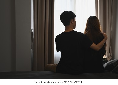 Back view of young man embracing his wife and sitting in bed room. Comforting, encouraging and understanding.