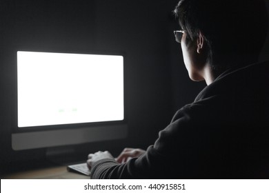 Back View Of Young Man In Glasses Using Blank Screen Computer In Dark Room