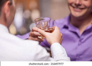 Back View Of Young Man Talking At Counter. Closeup Of Two Friends Sitting In Bar And Drinking Whisky