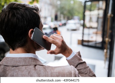 Back View Of Young Man Talking On Cell Phone On The Street Of City