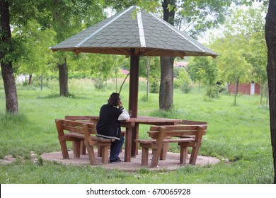 Back view of young man talking on cell phone in park