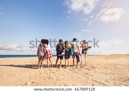 Back view of young men and woman standing on sea shore