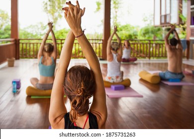 Back view of young people group practicing yoga with instructor. Stretching class at summer retreat camp to keep fit and health. Woman fitness, recreational sport activity on family holiday.