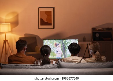 Back view of young people watching movies at home while sitting on sofa, focus on TV screen, copy space - Powered by Shutterstock